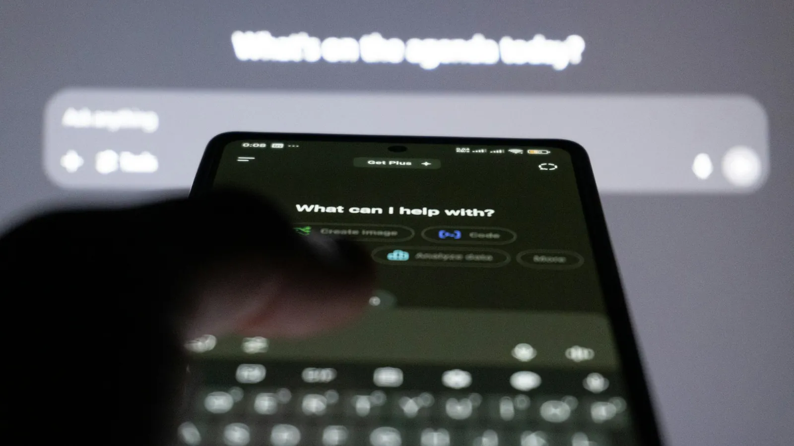 Application ChatGPT ouverte sur un smartphone, avec l'option de création d'image, devant l'écran d'un ordinateur